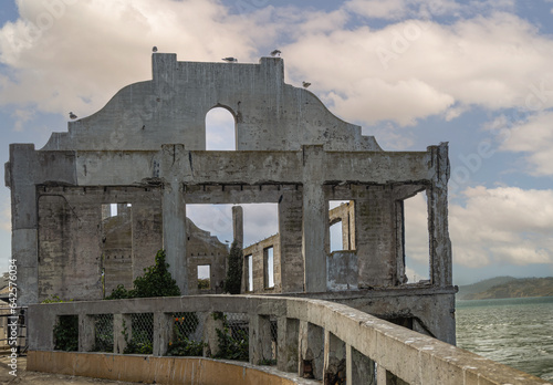 San Francisco, CA, USA - July 12, 2023: Alcatraz Island east shore look-through roofless ruin closeup under blue cloudscape. Greenish bay water
