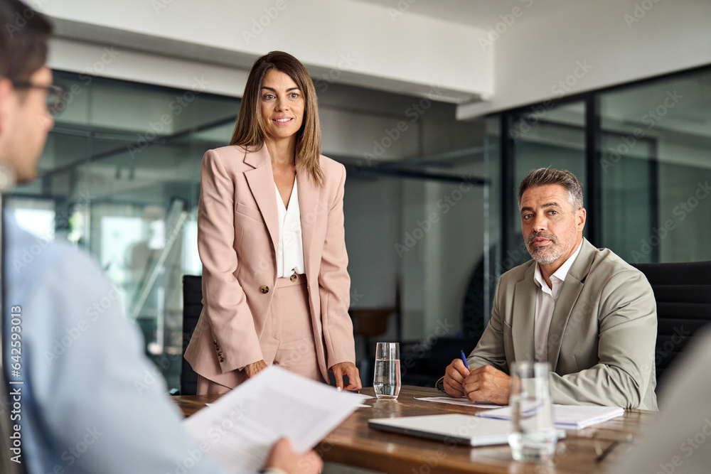 Fototapeta premium Busy business people having corporate business discussion at group meeting. Female executive mature Latin manager CEO leading team working together discussing project at office table.
