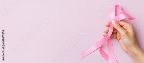 Pink ribbon held by a small girl in background Breast cancer awareness month Women s Day and World Cancer Day theme Copy space Panoramic