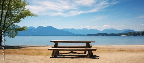 Sandy beach picnic table with lake mountain and blue sky view © vxnaghiyev