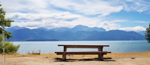 Sandy beach picnic table with lake mountain and blue sky view