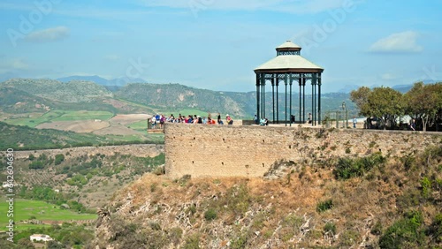 Mirador Observation deck at New Bridge Interpretation Center in Ronda, Spain. Tourists enjoying the valley views of the Centro de Interpretación del Puente Nuevo with a huge medieval arch bridge