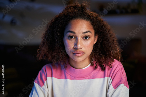 Close-up portrait of beautiful serious young latina woman. African American girl looking earnest at camera. Concentrating female indoors at night confident aptitude. Natural beauty in generation z.