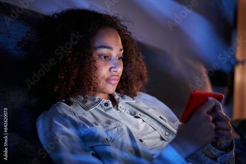 Tableau sur toile Serious Latin female watching videos on cell phone concentrating at home