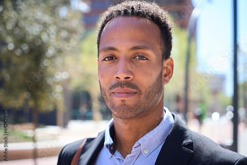 Close up portrait of young adult Latino business man with serious expression. Commercial male in formal wear looking earnest to camera outdoor. Professional worker outside blurred background city.