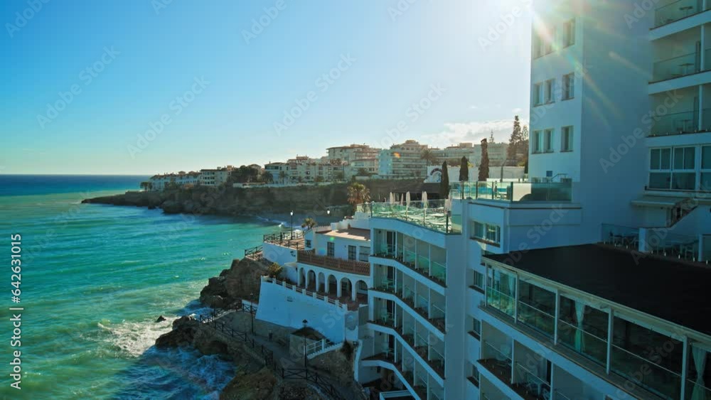 Beautiful Spanish Hotel Resort with Balconies and Sea View by in Nerja, Spain. People enjoying luxury Hotel in Plaza Balcón de Europa, Nerja with Mediterranean Turquoise Sea Views. Beautiful Spanish Hotel Resort with Balconies and Sea View by in Nerja, Spain. People enjoying luxury Hotel in Plaza Balcón de Europa, Nerja with Mediterranean Turquoise Sea Views.