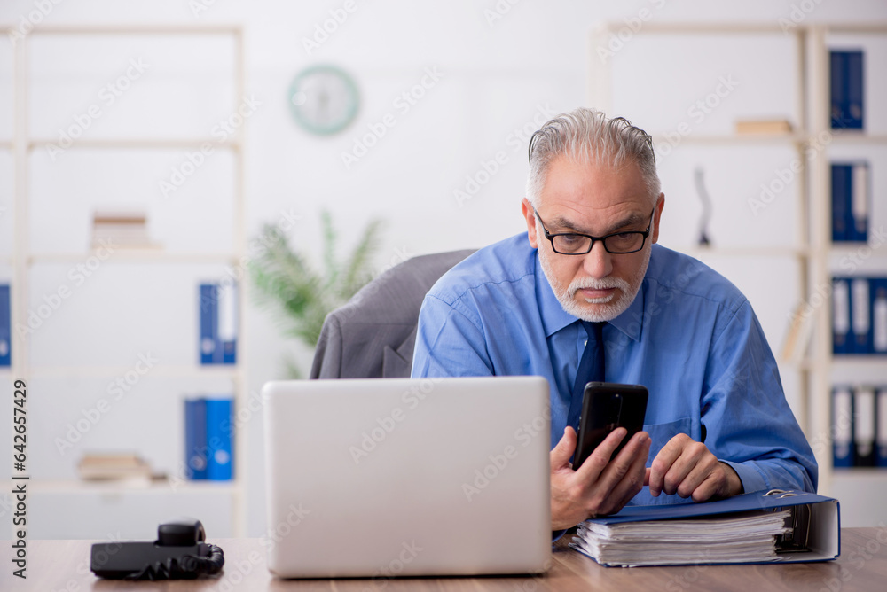 Old male employee working in the office Old male employee working in the office