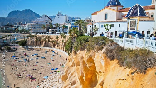 Tourists playing at Cala del Mal Pas Beach with Orange Cave Seashore in Benidorm. People having good time relaxing by the beach in Spain with crystal clear mediterranean Sea on a sunny day