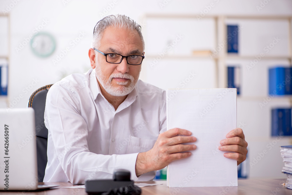Old male employee working in the office Old male employee working in the office