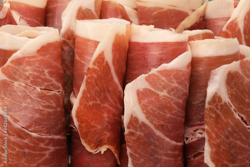 Rolled slices of delicious jamon as background, closeup Rolled slices of delicious jamon as background, closeup