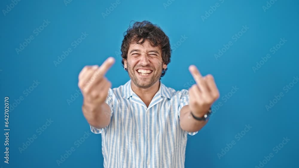 Young hispanic man smiling confident doing middle finger gesture over isolated blue background Young hispanic man smiling confident doing middle finger gesture over isolated blue background