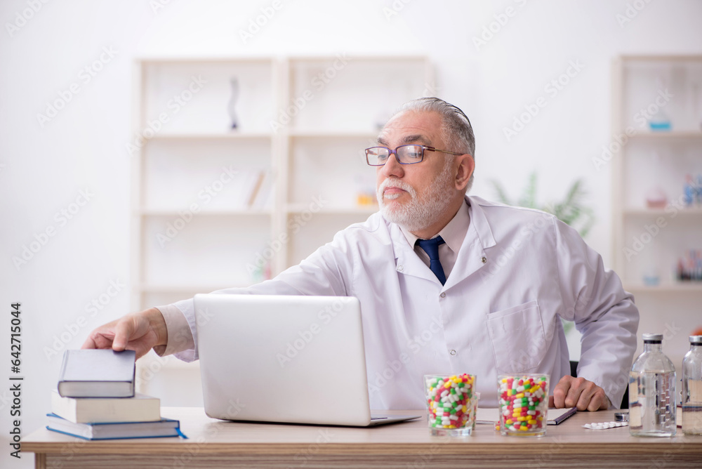 Old male doctor holding book in the clinic Old male doctor holding book in the clinic