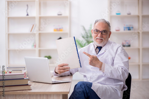 Old male doctor suggesting pills in the clinic