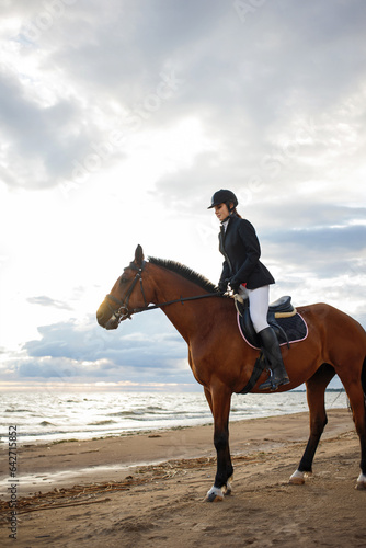 Equestrian sports. A young woman, a rider and her horse, portrait against a clear sky © Ulia Koltyrina