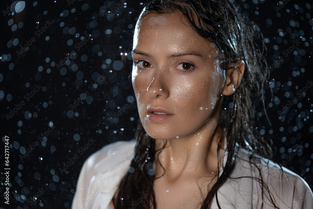 young woman in the rain, getting wet through, wet clothes and water running down her face. Stock