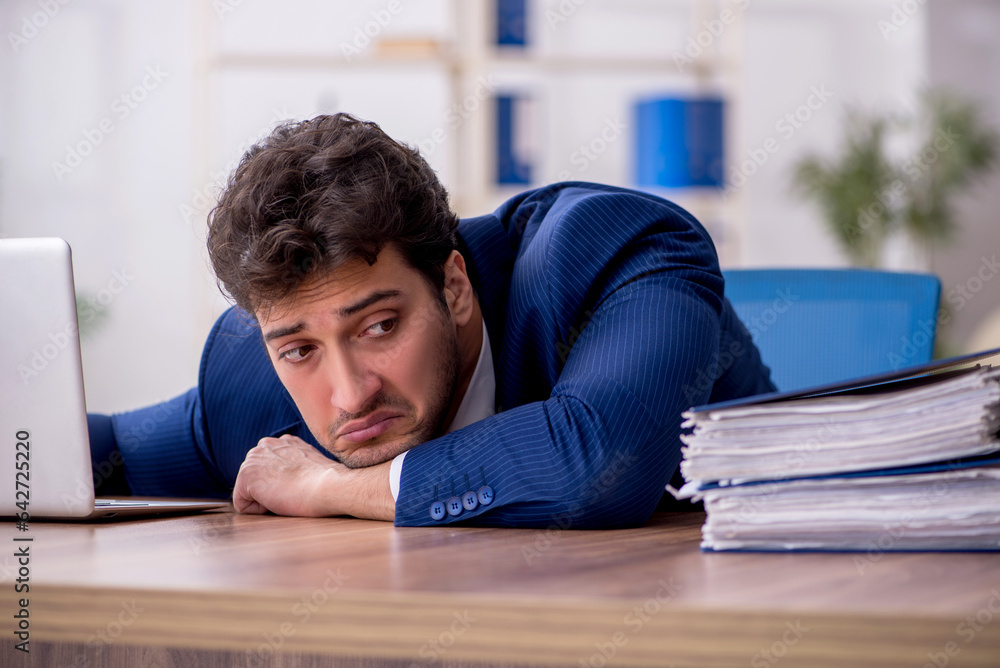 Young male employee and too much work in the office Young male employee and too much work in the office