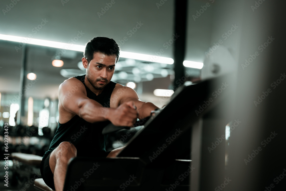 Motivated young asian sportsman having workout on rowing machine. Handsome man bodybuilder training body on modern block exercises in gym Motivated young asian sportsman having workout on rowing machine. Handsome man bodybuilder training body on modern block exercises in gym