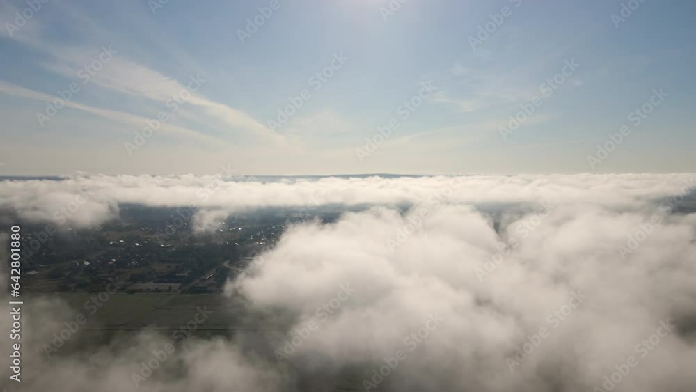 Aerial view from high altitude of landscape covered with puffy morning fog. Cold humid air condensing in rain clouds Aerial view from high altitude of landscape covered with puffy morning fog. Cold humid air condensing in rain clouds