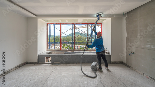 Laborer performing and polishing sand and cement screed wall on the construction site