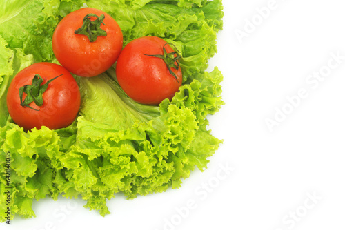 Three fresh tomatoes on salad leaves isolated on white background.