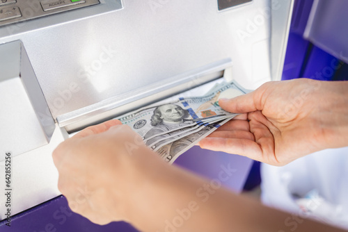 Young woman holding money in her hands after withdrawing the cash at the ATM
