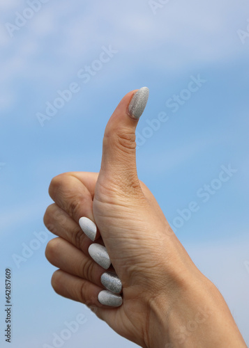 Thumb up of hand with nail polish on girl s nails as a symbol of OK