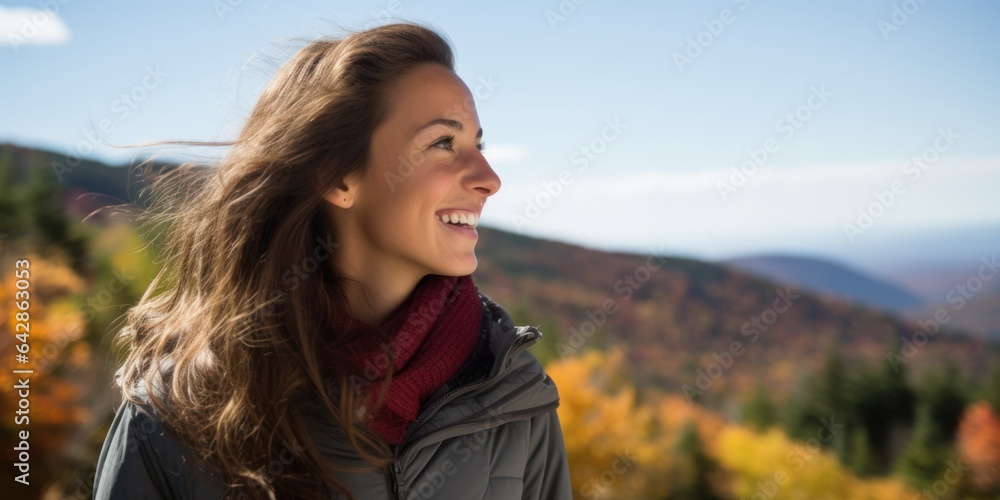 A woman stands with a sense of joy and wonder, surrounded by the vibrant colors of autumn leaves and the majestic beauty of a mountain in the distance