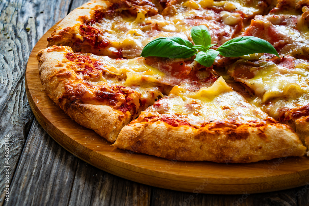 Pizza Serrano with cooked ham, mozzarella cheese and vegetables on wooden table
