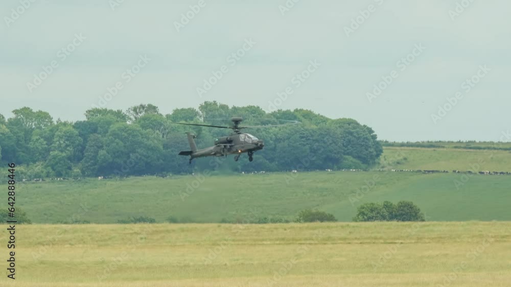 close-up front quarter view of ZM707 British army Boeing Apache Attack helicopter gunship (AH-64E, AH64E ArmyAir606) in low level flight over a grass field close-up front quarter view of ZM707 British army Boeing Apache Attack helicopter gunship (AH-64E, AH64E ArmyAir606) in low level flight over a grass field