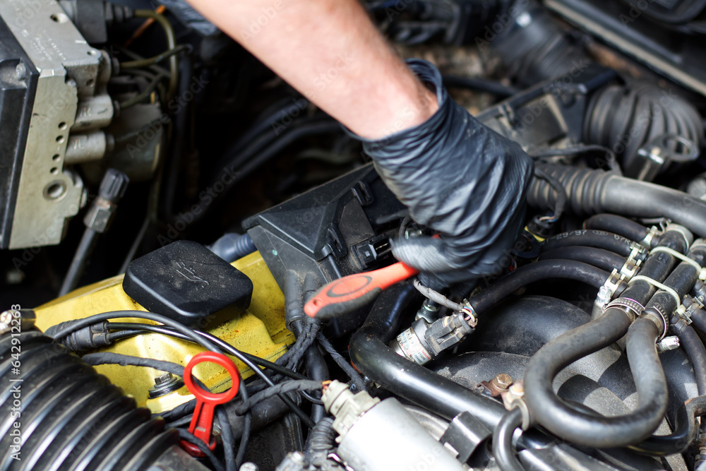 Hands of a master repairing the engine of an old European car.