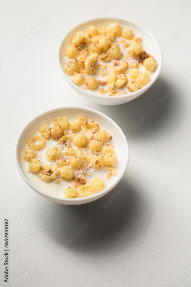 Breakfast with granola and milk in small bowls on a white background Breakfast with granola and milk in small bowls on a white background