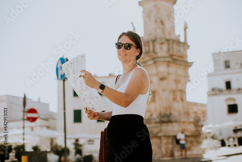 Female tourist with city map by the Saint Oronzo statue in Ostuni, Italy
