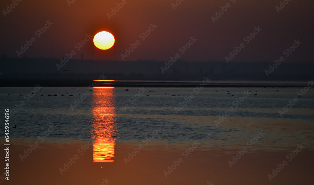 Sunrise over the lake, reflection of the red rays of the sun in the water, Ukraine, Tiligulsky estuary