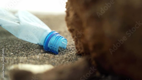 A plastic plastic bottle lies on the sand of the beach of the sea coast.
