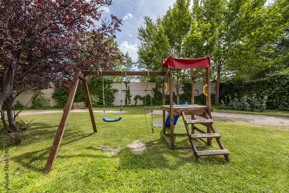 A wooden swing along with a slide on the grass