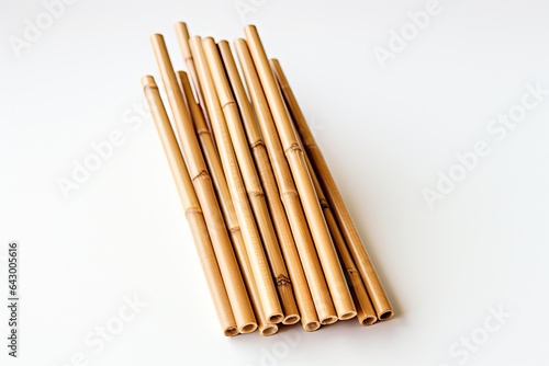 A close-up shot captures a pair of bamboo straws  which are environmentally friendly alternatives to plastic straws. The straws are photographed against a plain  white background.