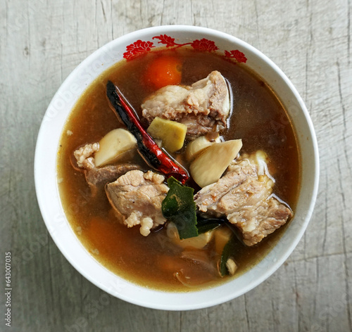 Top View of Tom Yum Pork with Clear Soup (Tom Yum Moo Nam Sai) has a distinctive sour and spicy taste. Food of Thailand. consists of Pork, dried chilies, tomatoes, galangal, kaffir lime leaves.
 photo