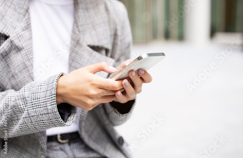 Unrecognizable businesswoman holding modern smartphone using mobile business application outdoors
