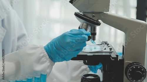 Health care researchers working in life science laboratory. Young female research scientist and senior male supervisor preparing and analyzing microscope slides in research lab.