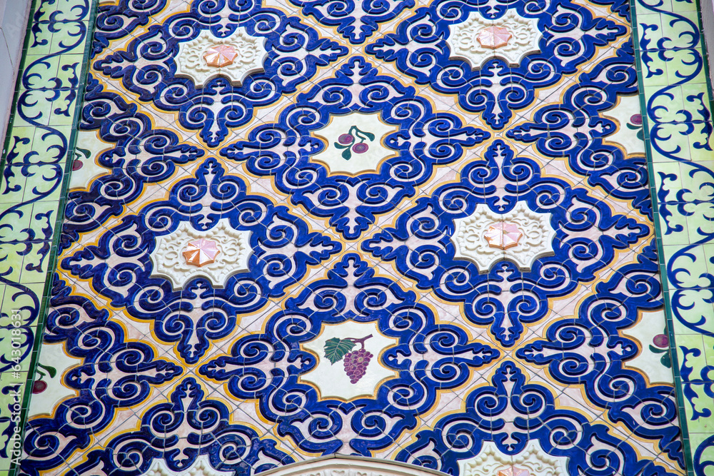 Facade finishing element. Squares of swirls of beautiful blue ceramics with clusters of grapes and cherries in the center. Architecture design details construction