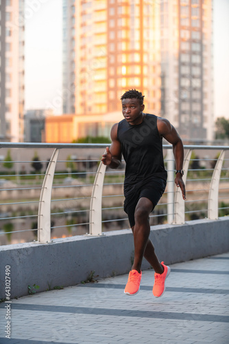 Confident African man in sportswear enjoying his morning jog with cityscape on background