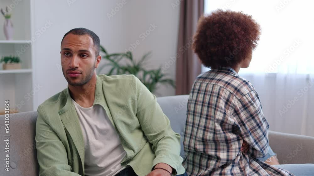 Angle view of multiracial marital couple sitting separately during meeting with marriage counselor in office. Upset man and woman facing family issues and avoiding communication with each other Angle view of multiracial marital couple sitting separately during meeting with marriage counselor in office. Upset man and woman facing family issues and avoiding communication with each other