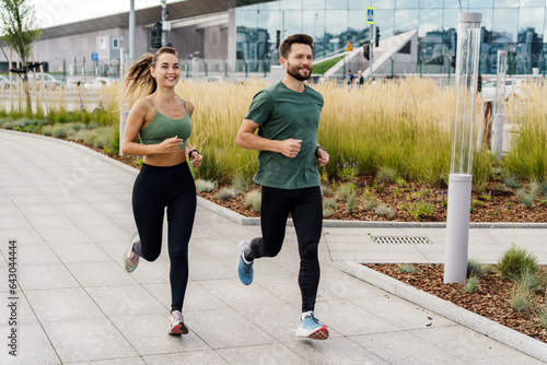 A fitness trainer and a woman training in sportswear and sneakers.  Runners are a young couple training on the street. Athletes are friends of running exercises. Use a fitness watch.