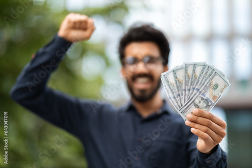 Cash money dollar banknotes in excited eastern man hand