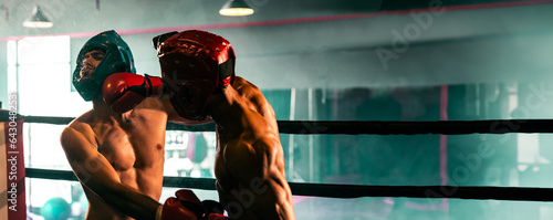 Two athletic and muscular body boxers with safety helmet or boxing head guard face off in fierce boxing match. Boxing fighter competitor fighting in the boxing ring. Spur