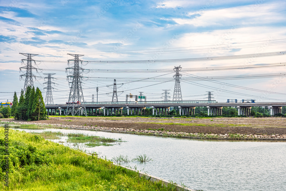 High voltage power tower and highway with river scenery