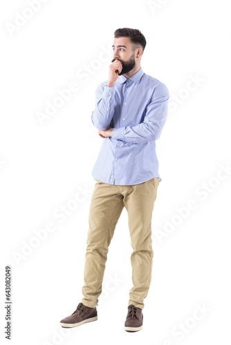Young bearded adult business man in formalwear thinking and looking up with hand on chin. Full body length portrait isolated on transparent background.