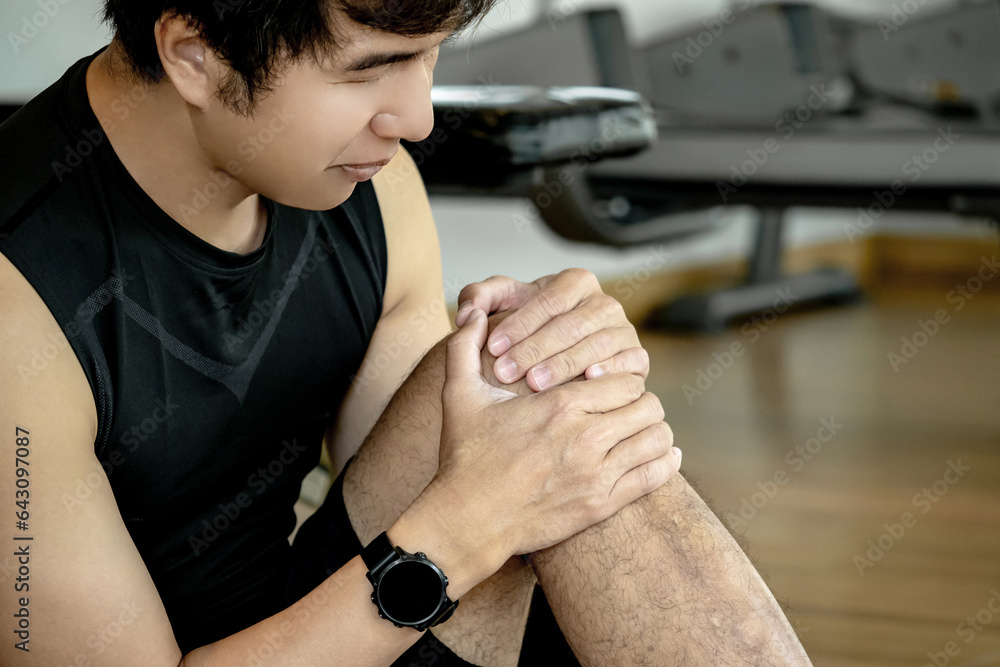 Asian sport man feeling knee pain or rheumatoid arthritis while sitting