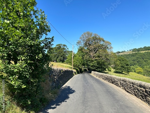 Rural landscape, with a country road, dry stone walls, trees, fields, and hills in, Sowerby Bridge, UK photo