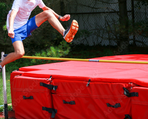 фотографія Teenage boy jumping over a high jump bar like he is hurdling